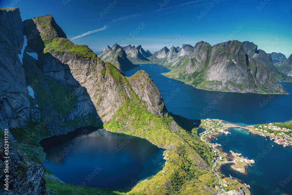 Reine, Lofoten, Norway. The village of Reine under a sunny, blue sky, with the typical rorbu houses. View from the top of Reinebringen mountain. - obrazy, fototapety, plakaty 