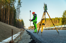 Surveyor Engineer With Equipment (theodolite Or Total Positioning Station) On The Construction Site Of The Road Or Building With Construction Machinery Background