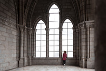 Latin Woman Standing Behind Large Windows In A Cathedral