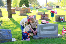 A Boy Scout, Cub Scout And Their Leader Place American Flags On Veteran Graves