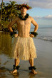 Male hula dancer poses with a power move at sunset by the beach.