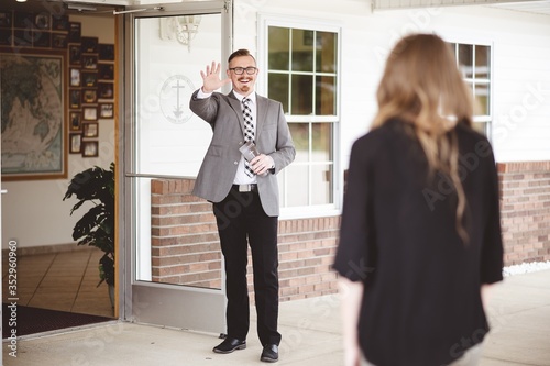 Fotografía Man in suit outside a church waving and welcoming a woman