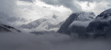 Fototapeta  - Wysokie szczyty górskie pokryte gęstą mgłą