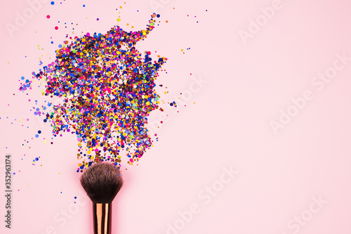 Fotomural Closeup of professional cosmetic makeup brush with explosion of shiny colorful sparkles on bright pink background with copyspace for your text