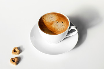 Happy morning drink. Cup of tasty espresso on white table with two peaces of sugar.