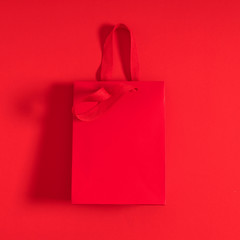 Wall Mural - Red gift bag on red background. Flat lay, top view, copy space