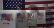 © vesperstock - Profile, medium shot, young man and two women, one Hispanic, in polling station, semi-transparent as they vote in booths during election with US flag in background.