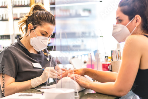 Manicure and pedicure salon with security measures and people with masks, performing a pedicure treatment. Reopening after the corod-19 pandemic. Coronavirus