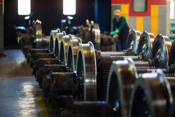 Axles with wheels of railway cars lie in a row at a repair plant