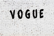 Word vogue painted on white brick wall