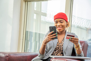 Wall Mural - beautiful young african business woman using his credit card and mobile phone, smiling