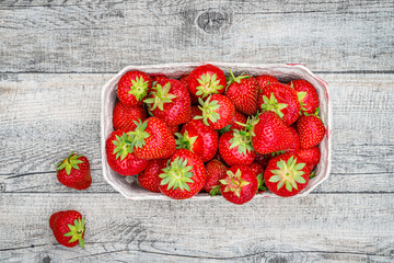 Wall Mural - Fresh German strawberries in carton paper boxes on wooden table, top view.  Red strawberry berrees harvesting concept