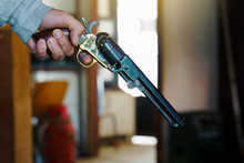 Close Up On Hand Of Unknown Caucasian Man Holding Old Black Powder Percussion Army Revolver Vintage Gun Replica Civil War Old Wild West Style In Room In Day Side View