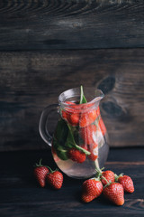 Jug of summer refreshing strawberry and spinach lemonade. Vitamin drink. Homemade infused water with fresh berries. Tasty cold seasonal beverage