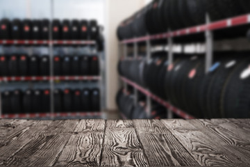 Canvas Print - Empty wooden surface and blurred view of car tires in auto store, closeup. Space for text