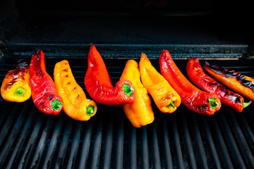 Several yellow and red cooked peppers on a barbeque