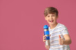 © Pixel-Shot - Sporty little boy with water showing thumb-up on color background