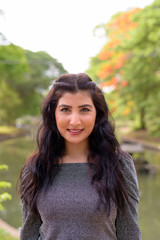 Face of happy young beautiful Indian woman smiling at the park outdoors