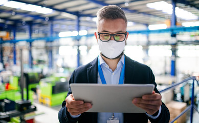 Wall Mural - Technician or engineer with protective mask and tablet working in industrial factory.