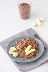 Buckwheat porridge on a plate with quail eggs and two slices of butter. Healthy food concept. Copy space.