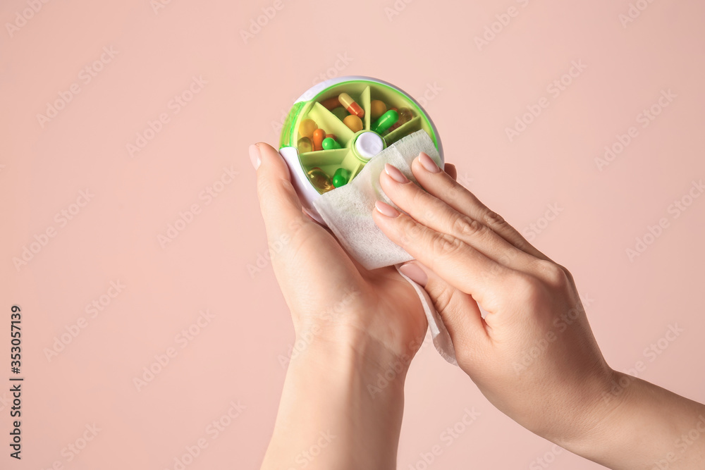 Woman disinfecting stationery on color background