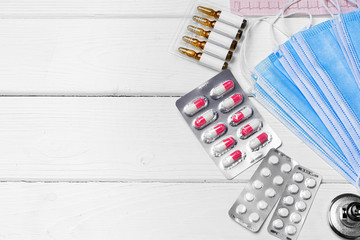 Medical equipment. Stethoscope, mask and pills on wooden desk close up