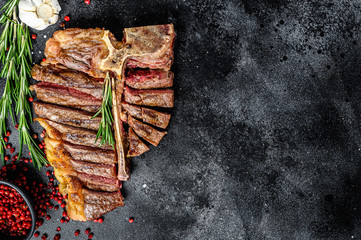 Grilled T-bone steak. Cooked tbone beef. Black background. Top view. Copy space