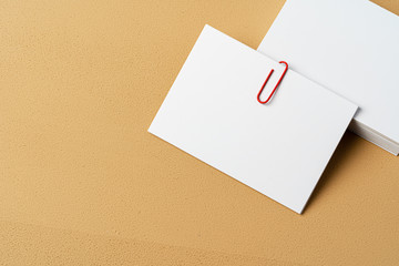 Poster - Pile of white businesscards with a clip on beige background