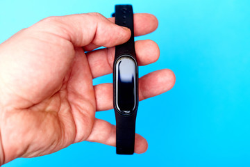 Wristband watch, in a male hand on a blue background. Health monitoring device.