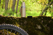 Photo of a thermos and bicycle wheels in the summer outdoors forest. Tourist vacation concept.