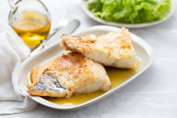 Sticker - fried cofish with garlic and olive oil on white dish on ceramic background