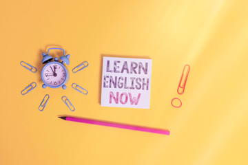 Poster - Writing note showing Learn English Now. Business concept for gain or acquire knowledge and skill of english language Alarm clock wakeup clips rubber band pencil notepad colored background