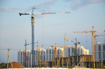 Inside place for many tall buildings under construction and cranes under a blue sky working on place with tall homes