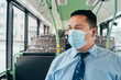 bus driver wears blue face mask.  alone in bus.