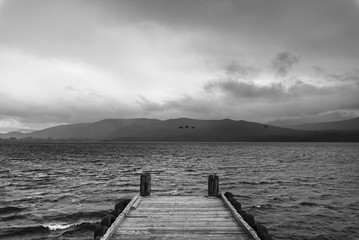  wooden dock in the lake with raining at mountain background, black and white