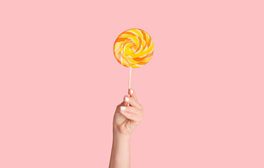 Wall Mural - Young girl with colorful swirl lollypop on pink background, closeup. Panorama