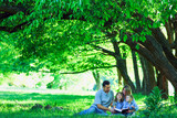 Fototapeta  - young family reading the Bible in nature