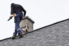 Roofer Construction Worker Repairing Chimney On Grey Slate Shingles Roof Of Domestic House, Sky Background With Copy Space.
