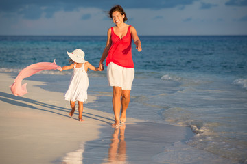 Wall Mural - Mother and little daughter walking on sunny beach on Maldives at summer vacation