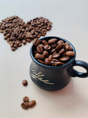 Mug with coffee beans. In the background is a heart made of coffee beans.