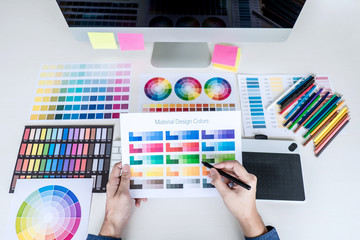 Poster - Image of male creative graphic designer working on color selection and drawing on graphics tablet at workplace with work tools and accessories, top view workspace