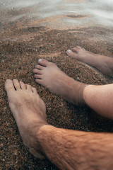 Feet of a man and a woman relaxing in the water at the seashore