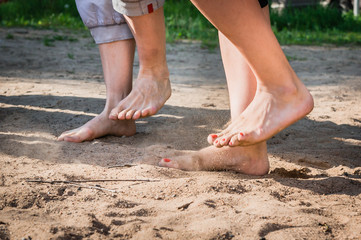 A man and a woman with bare feet stomp on the sand barefoot