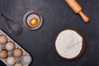 Eggs, flour and rolling pin on a dark background. Free space for text.