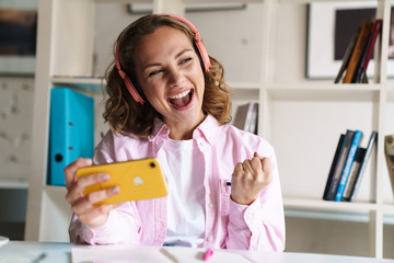 Canvas Print - Photo of excited woman in headphones playing video game