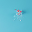 © loominatis - Trendy gift concept with frozen melting ice cube as a present wrapped in red ribbon on blue background.