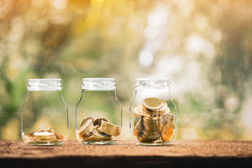 Clear bottle with gold put inside with growing value and collect money put on the wood in the morning sunlight, Business investment and planning to saving money for future spending concept.