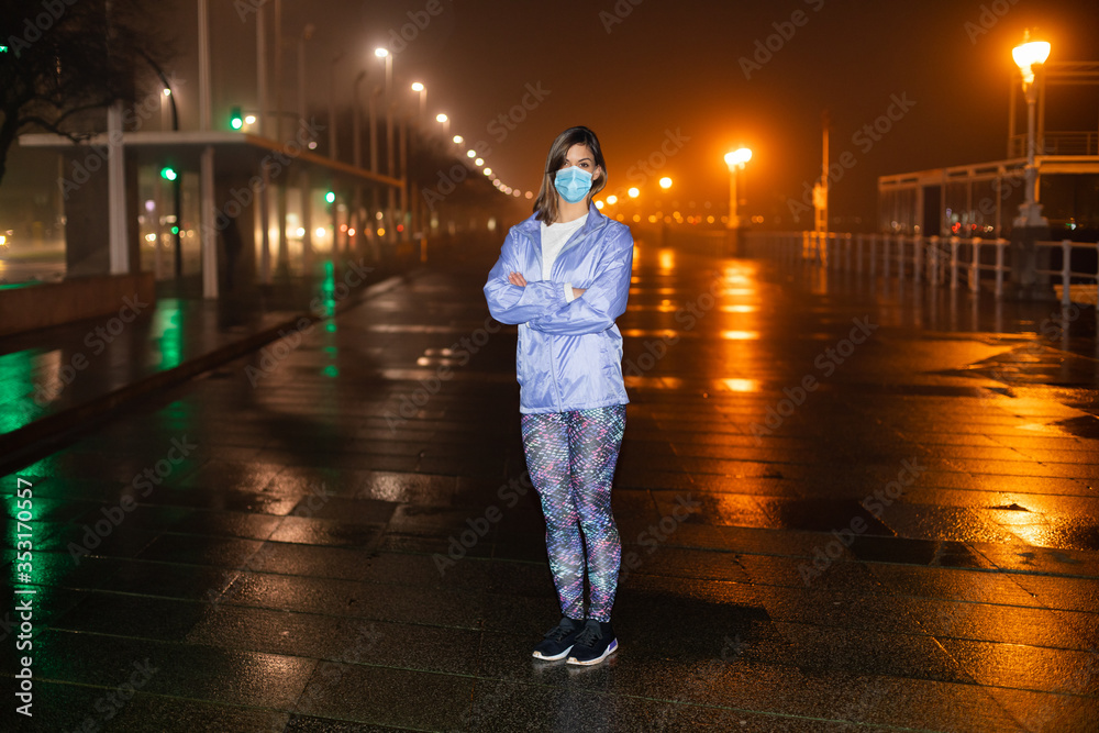 Condifent female athlete on urban night fitness and running workout wearing face mask against Covid-19. - obrazy, fototapety, plakaty 