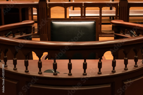 A witness stand with a black seat in the court room infront of tribunal when witness testify of evidence to judge, they will sit at here for testimony of witnesses, it is vintage or retro style