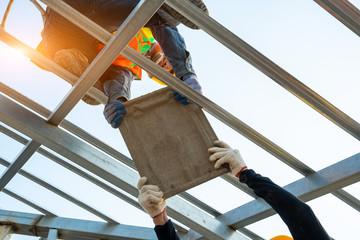 Poster - Roof repair,Construction worker using nail gun to install new roof on top roof,Residential building under construction concept